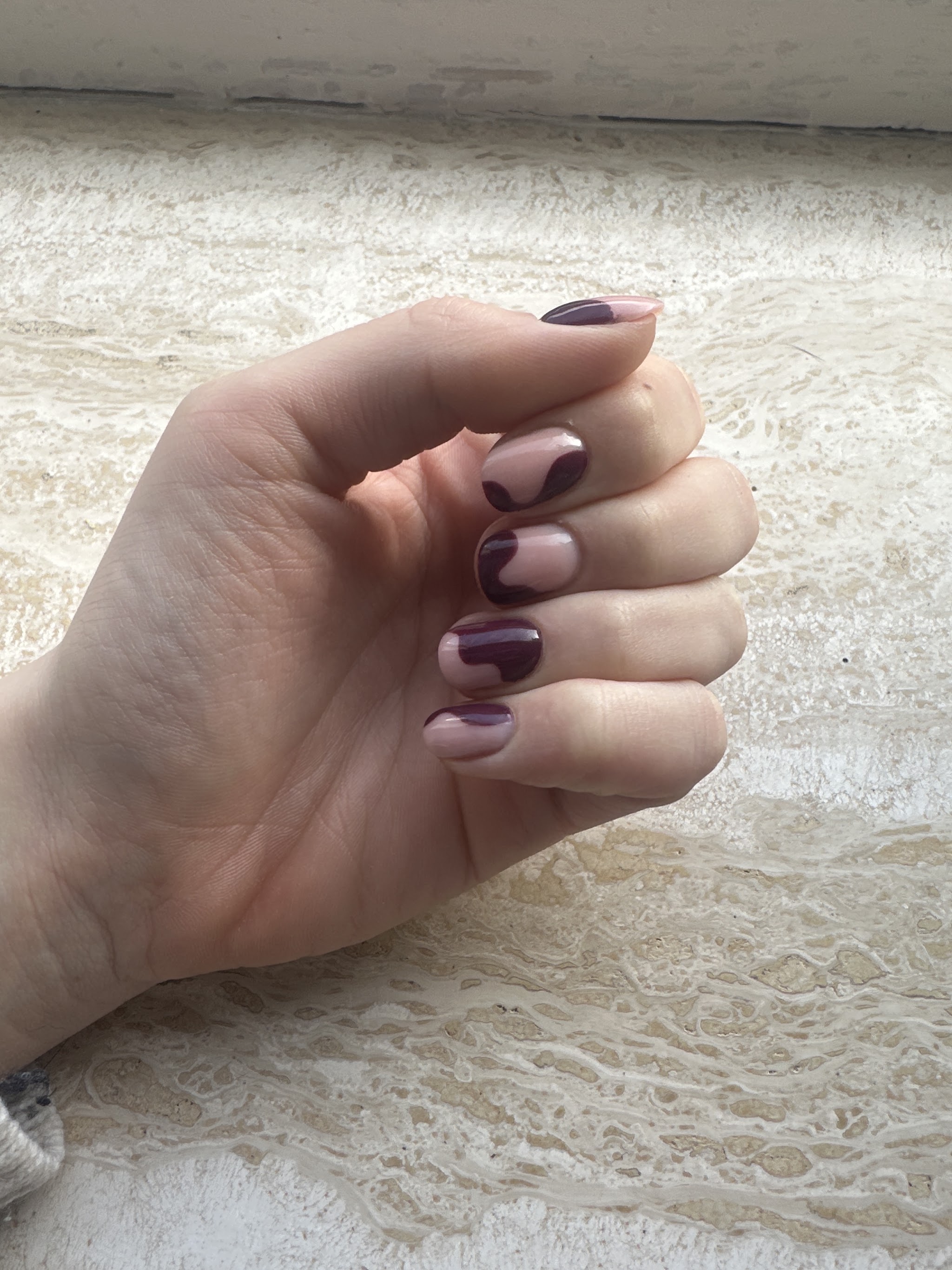 Nagels met pruimkleurige golfjes op een kanten achtergrond